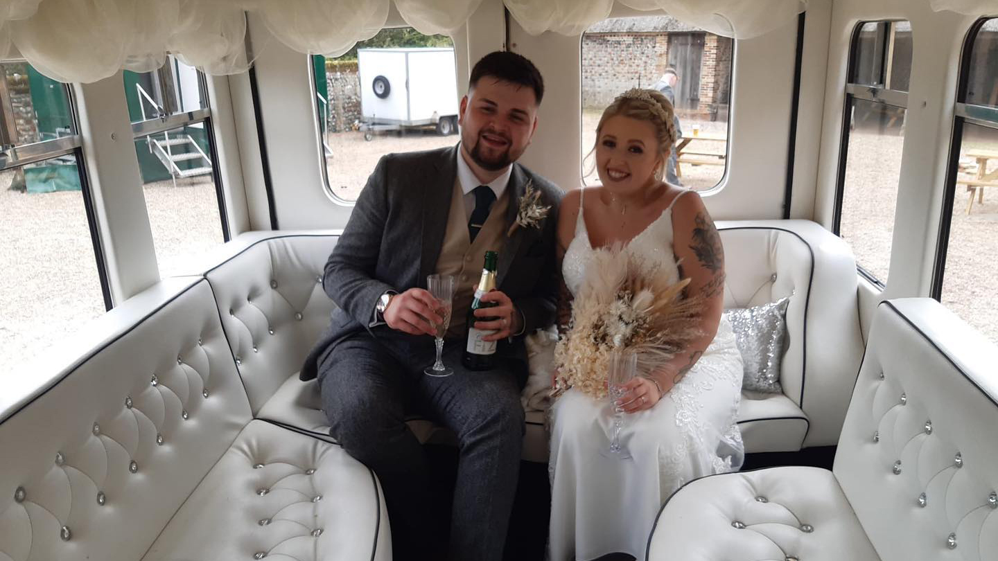 Bride and Groom holding a glass of champagne seating inside the Asquith Bus