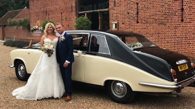 Bride and Groom Standing in front of a classic Ivory Daimler Limousine with balck roof