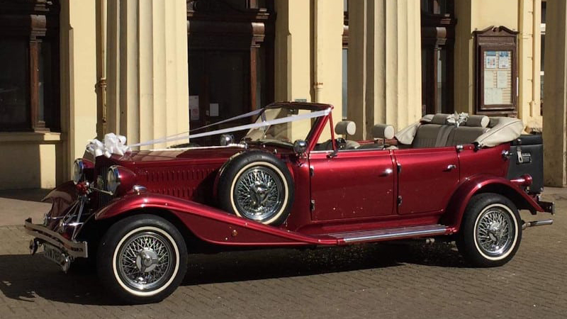 Left side view of Burgundy vintage Beauford with roof down, decorated with White Ribbons parked in front of Registrar in Norwicj