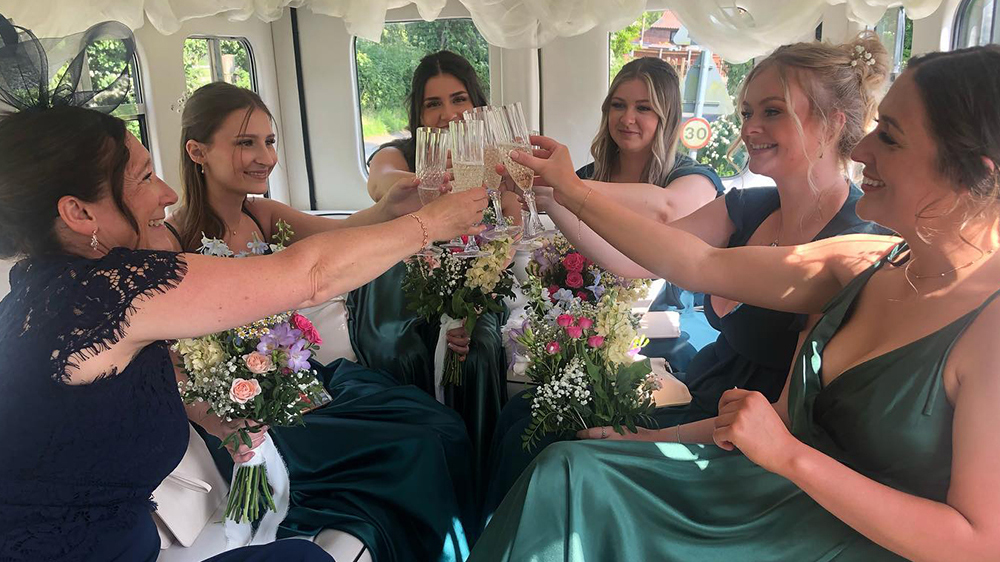 Bridesmaids and Bride toasting with a glass of Champagne inside the Vintage Asquith Bus