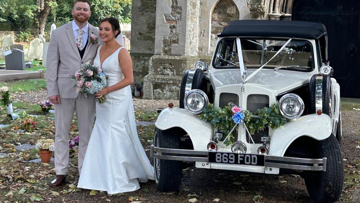 Bride and Groom with Vintage Beauford posing for photos in front of a church