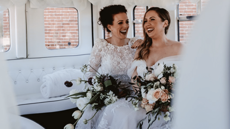 Two laughing Brides seating inside the vintage asquith bus