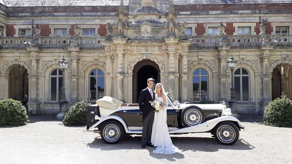 Bride and Groom with a Vintage Beauford in Black & White posing for photos in front of Somerleyton Hall wedding venue.