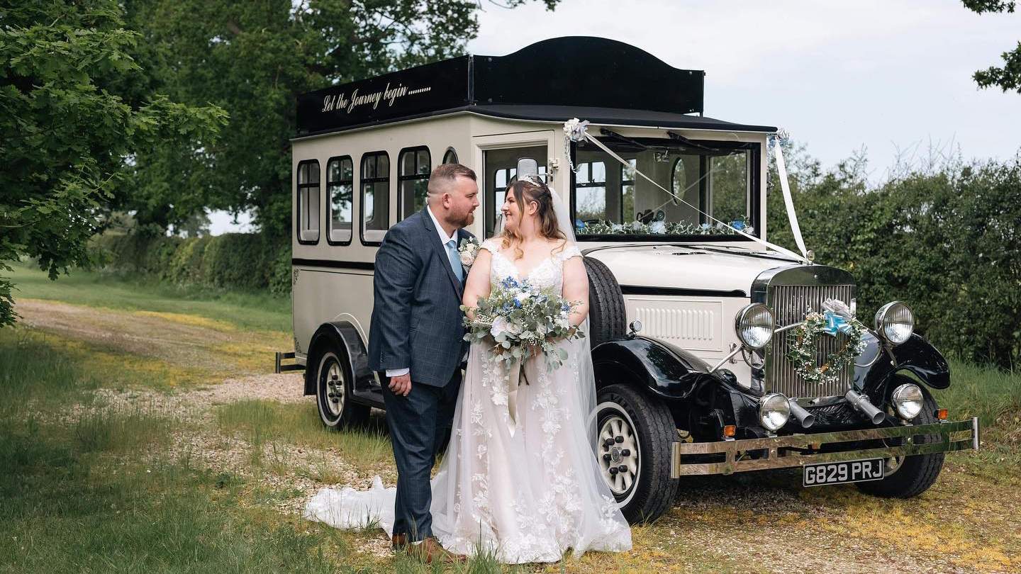 Bride in her white wedding dress holding a bouquet of flowers in front of a Black & Ivory Wedding Bus