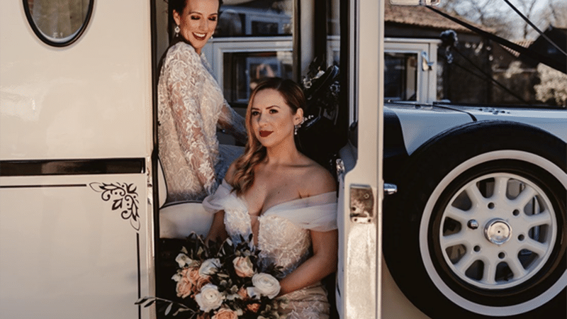 Two Brides wearing designers white wedding dresses posing for photos with the Ivory Asquith