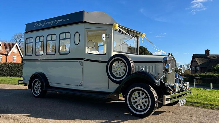 Vintage ivory bus with black wheel arches parked on the road