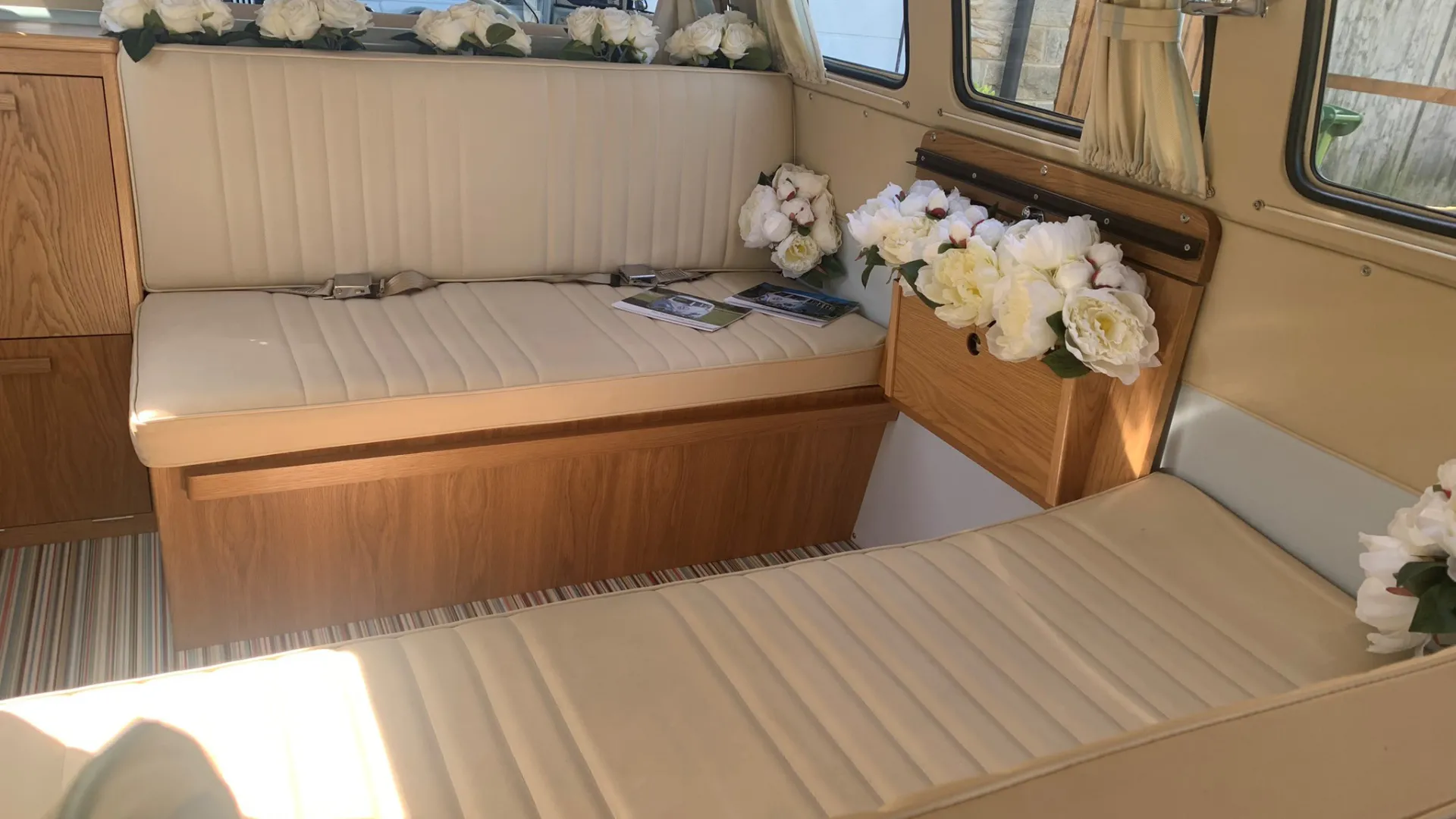 Cream interior bench seats in the rear of a classic campervan. Both bench seats are facing each others.