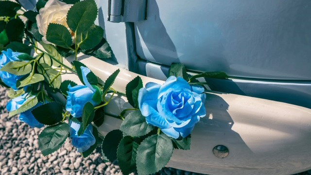 Blue Flowers with green foliage decoration attached to front bumper of Campervan