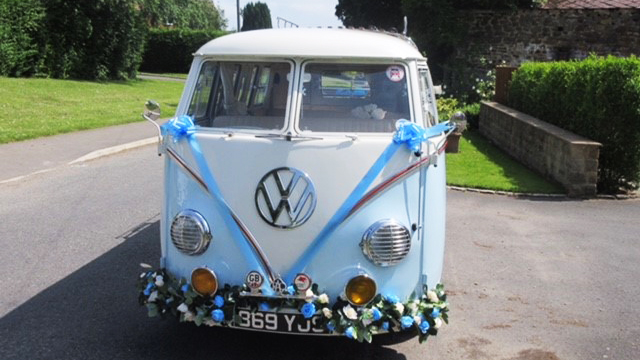 Full front view of classic VW campervan with blue ribbons and bows and flower decoration