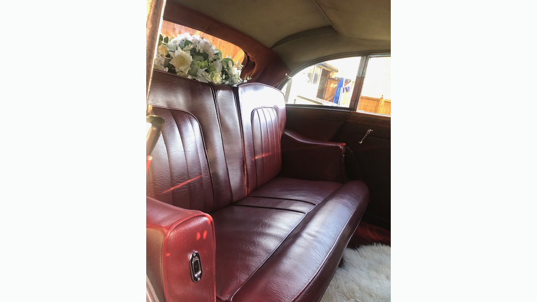 red leather rear seats inside rolls-royce with wedding flower decoration on rear parcel shelf