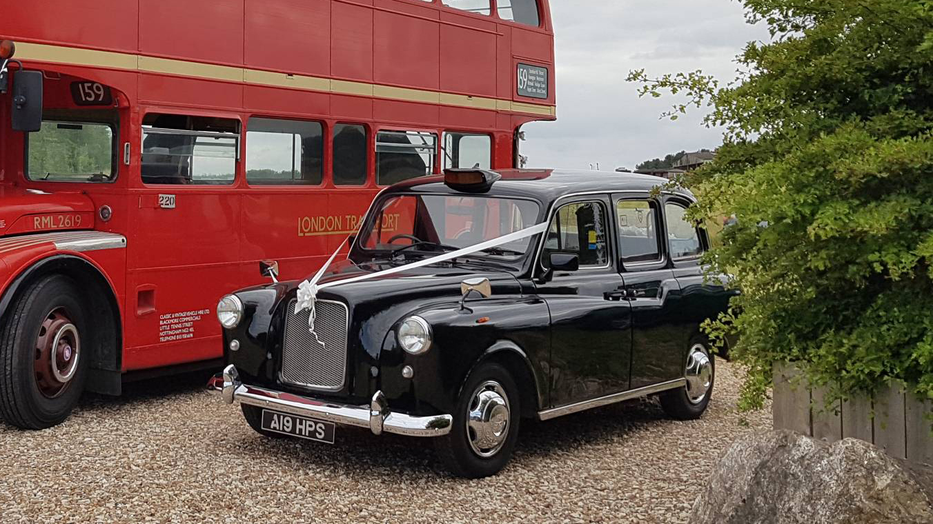 Black Taxi Cab with White Ribbons parkes nest to a Double decker red routemaster bus