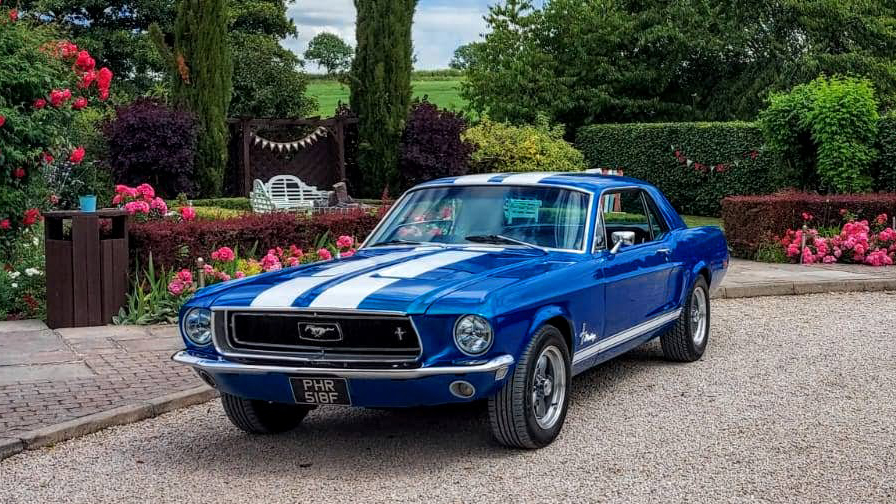 Front left side view of Classic Blue Ford Mustang at a wedding venue