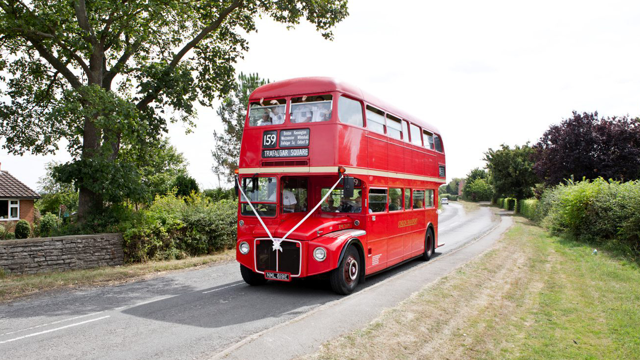 Bis Red Double Decker Routemaster Bus with white ribbons and passengers waving inside