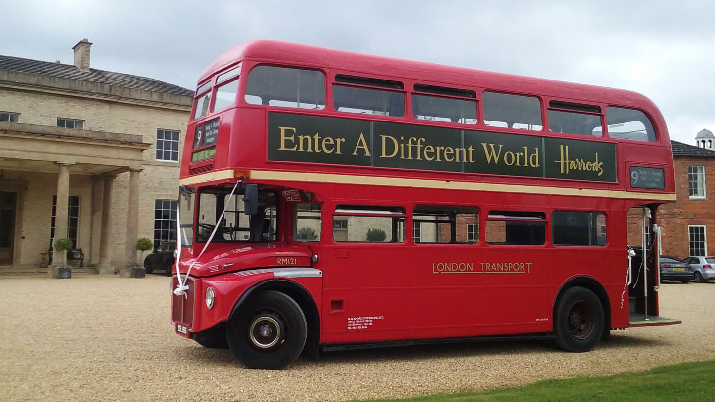 Vintage Red Routemaster bus with White ribbons in front of wedding venue