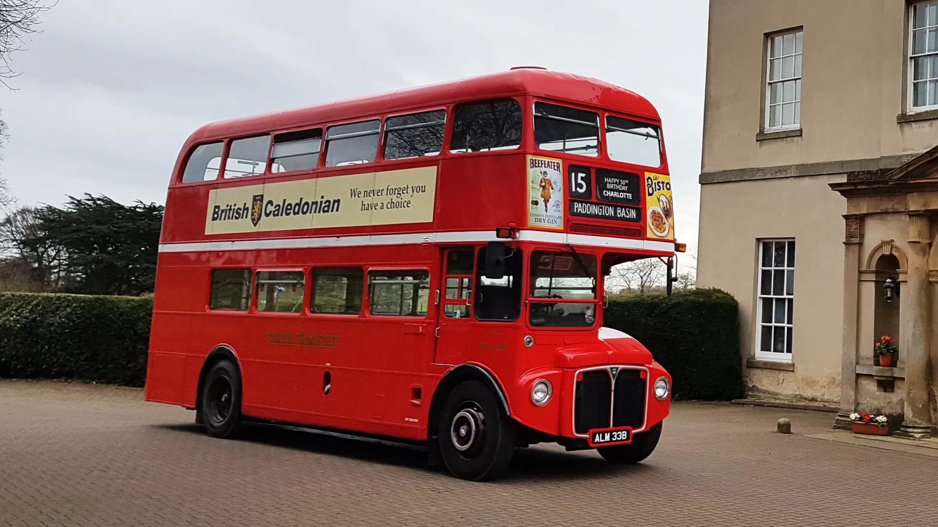 Vintage Red Double Decker routemaster bus with period advertising on its right side