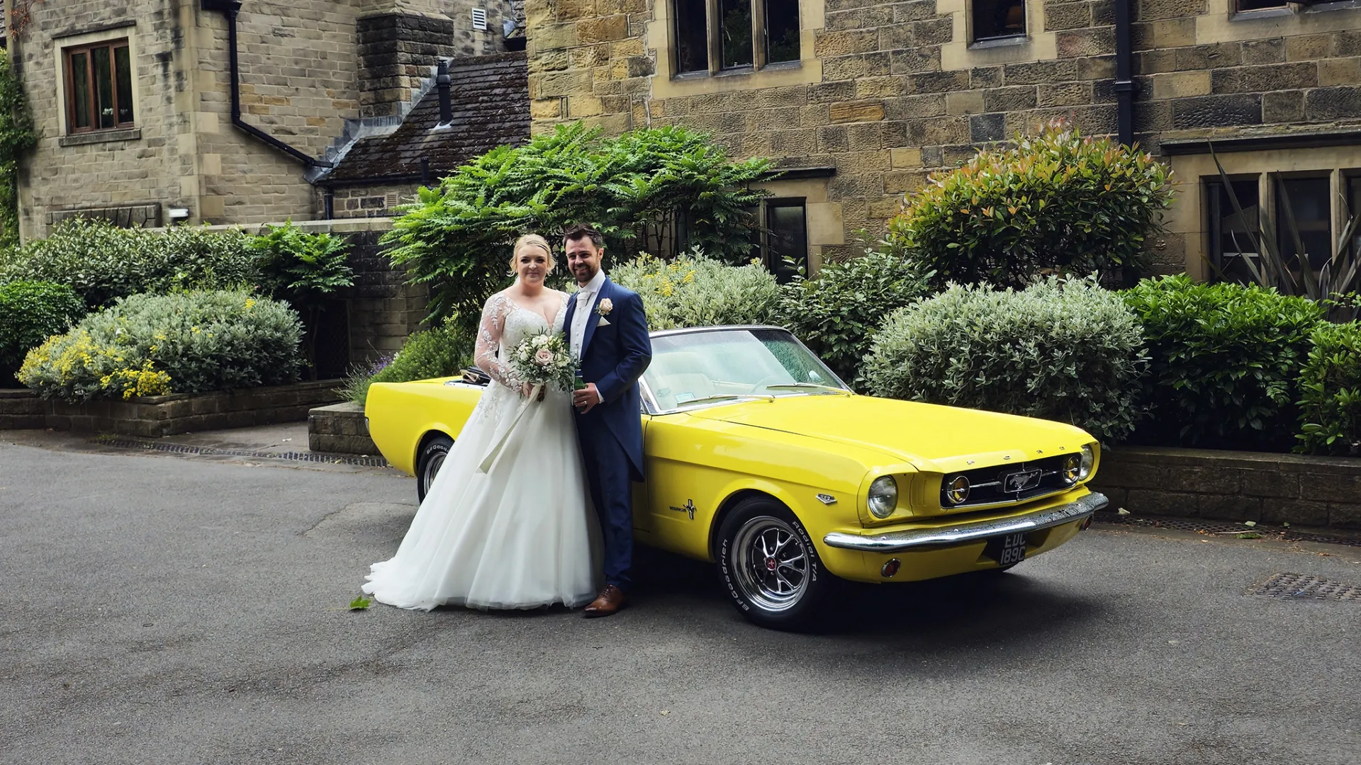 Bride and Groom standing in front of a yellow classic Ford Mustang