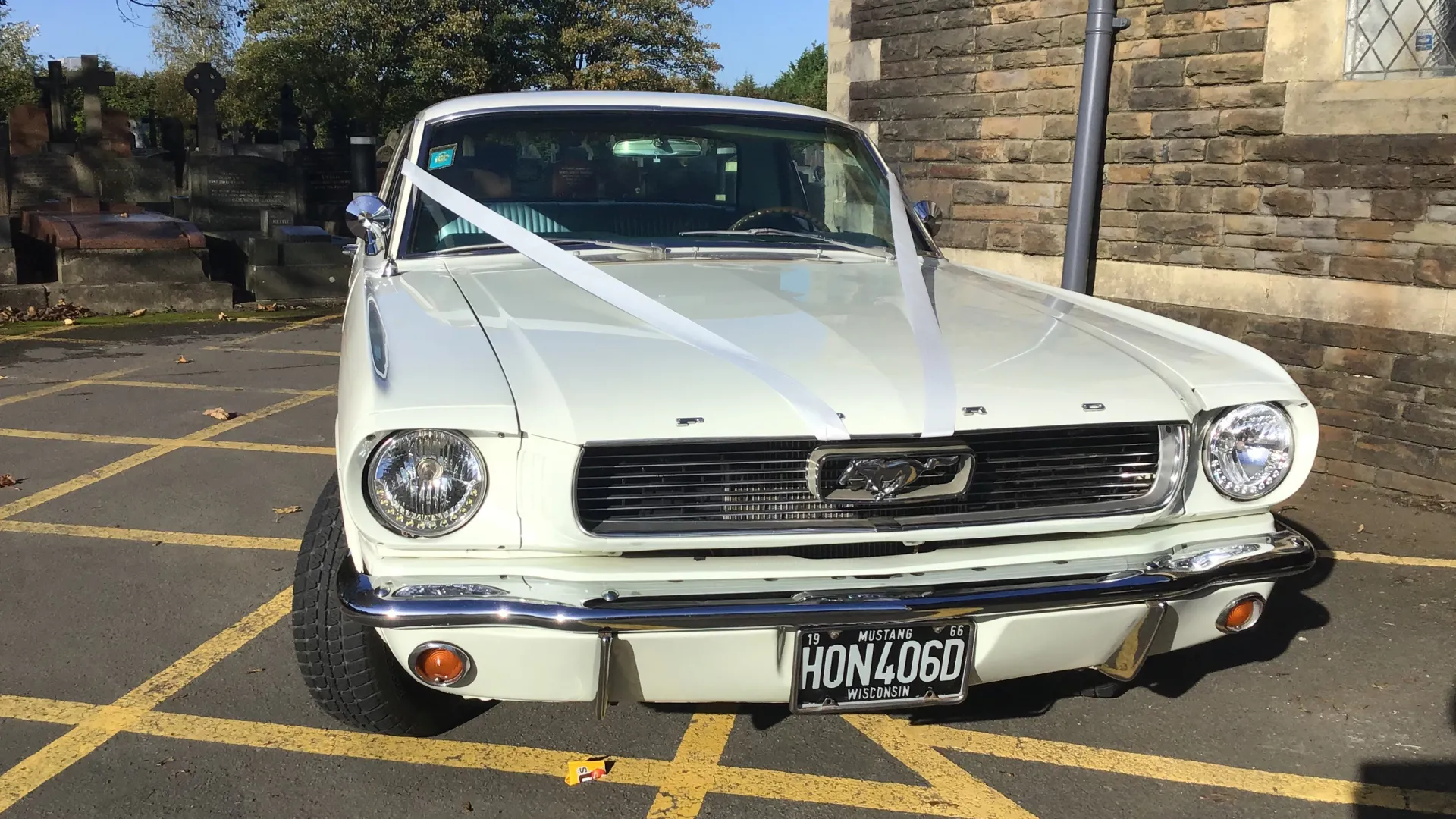 Front view of Classic White Mustang with white wedding ribbons