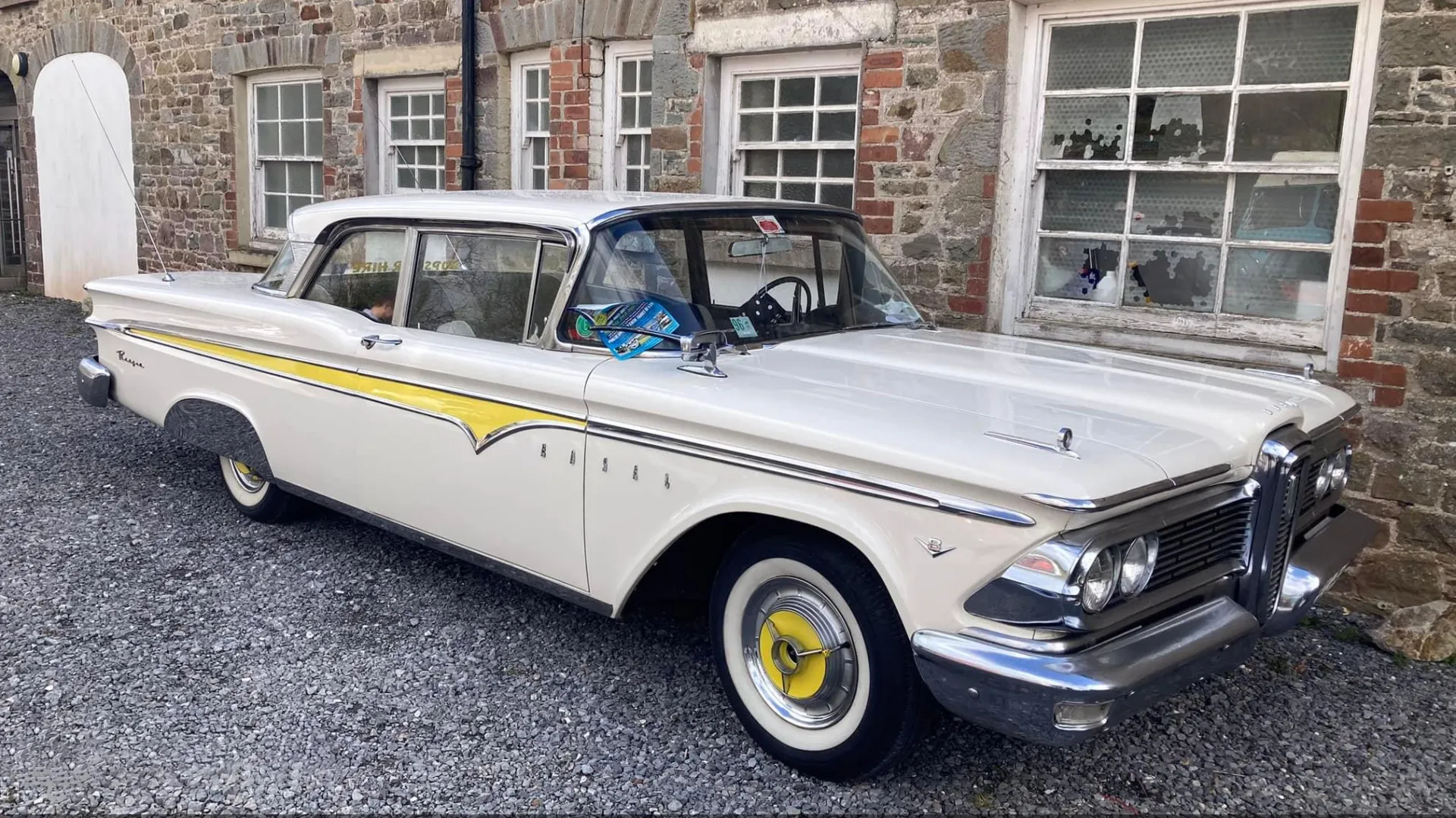 Ivory Ford Edsel with yellow lines on the side of the vehicle with gold chrome wheel caps