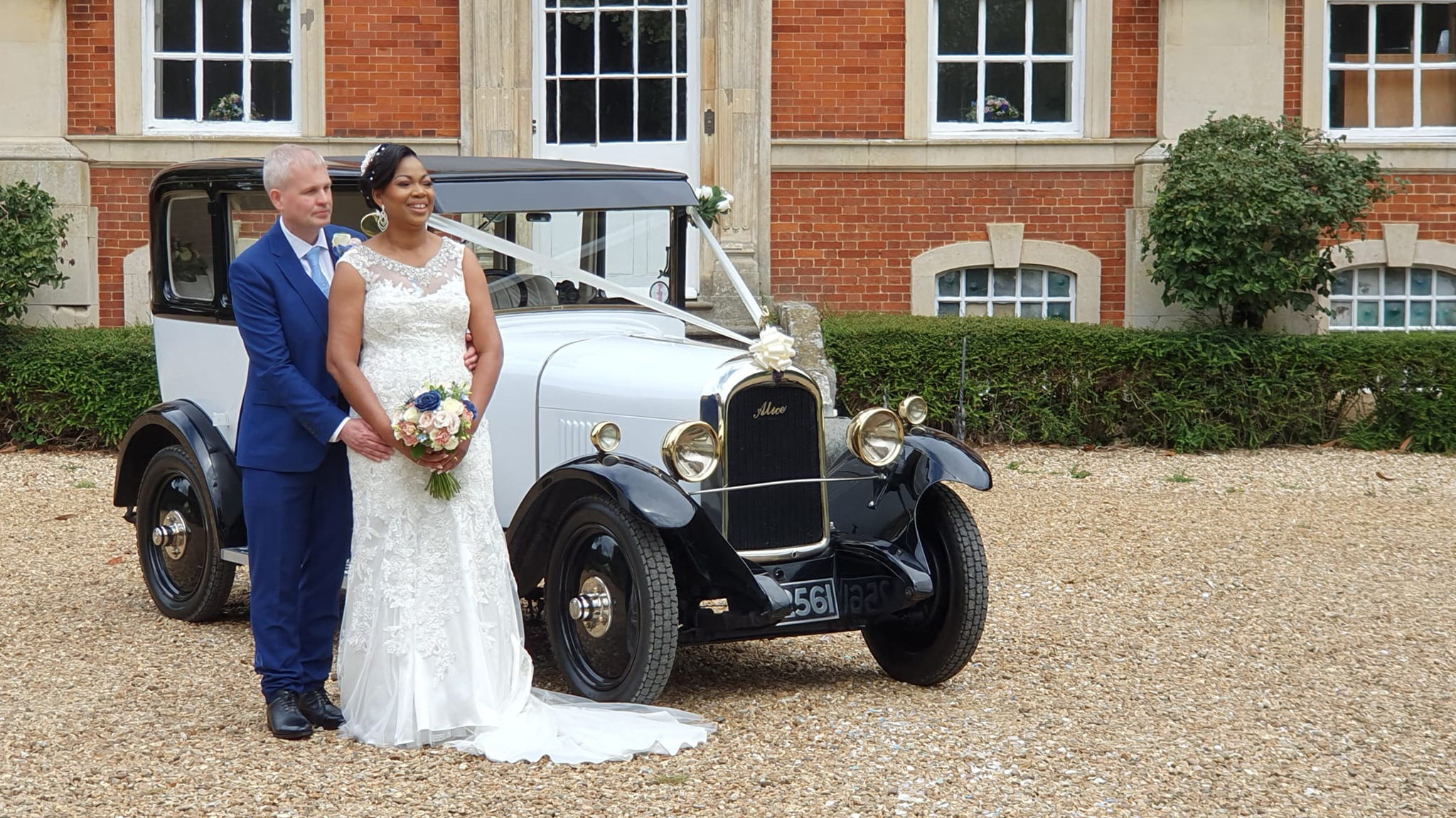 White vintage Citroen in front of a wedding venue in Coventry with Bride wearing a white dress and groom in a blue suit