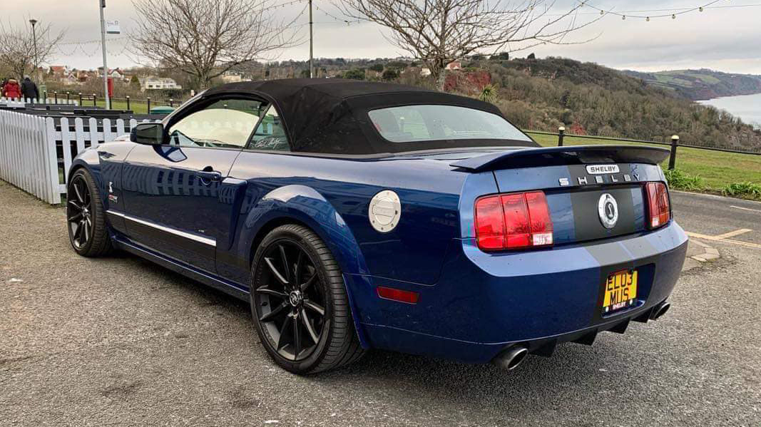 Rear view of Modern Ford Mustang Shelby with black soft top roof closed.