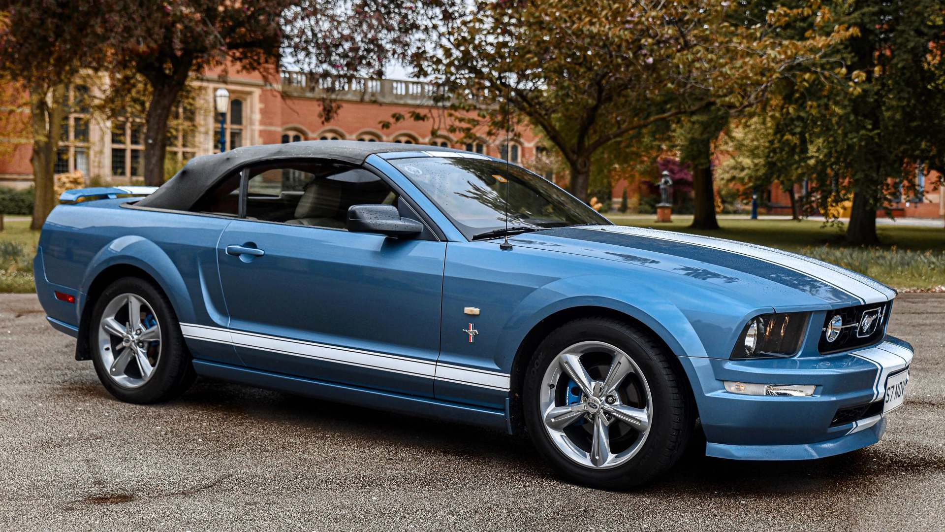 Right side view of Convertible Mustang in Blue with white stripes and roof up