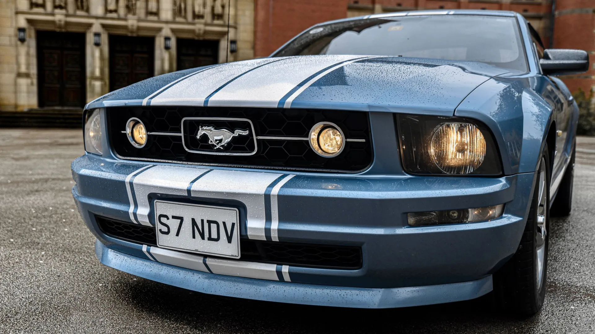 Front view of Modern Ford Mustang with lights on.