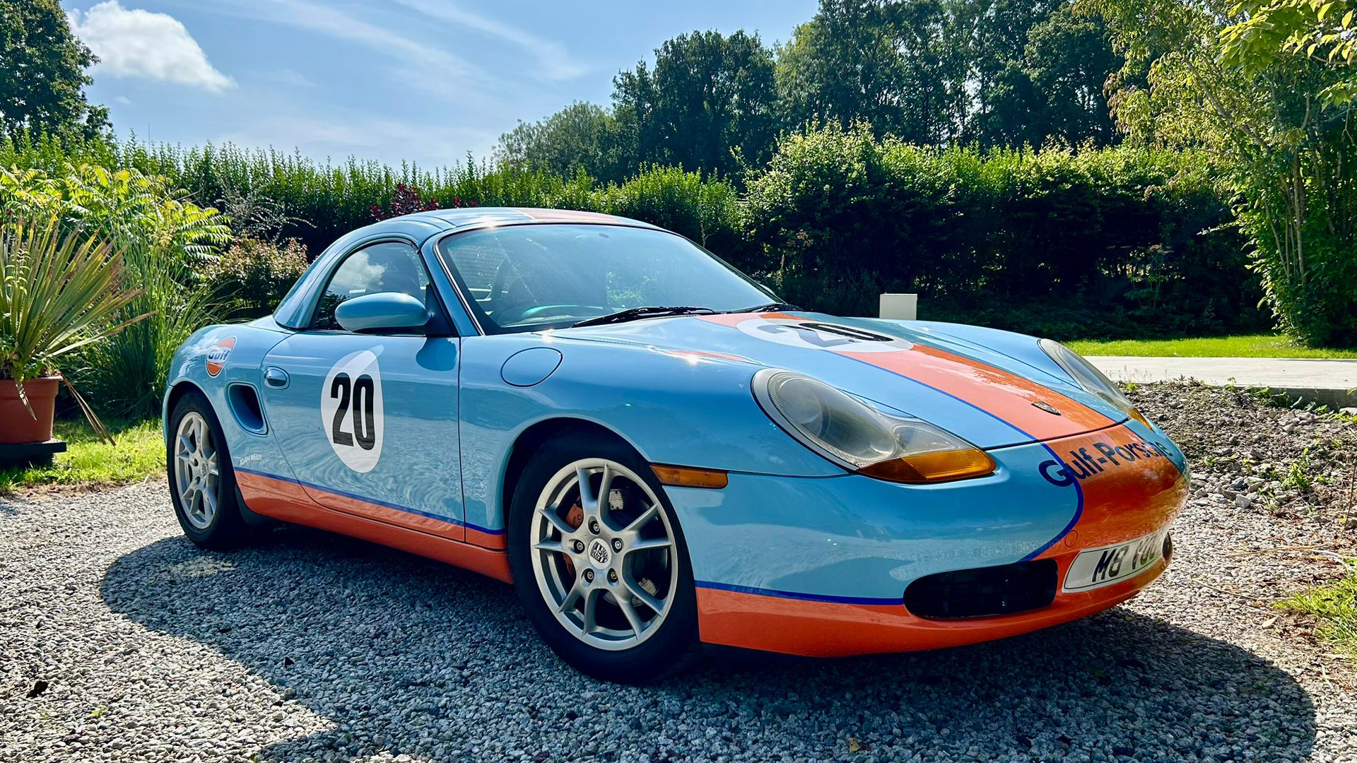 Side view of Porsche Boxster Guld Livery in Light Blue and orange with chrome wheels