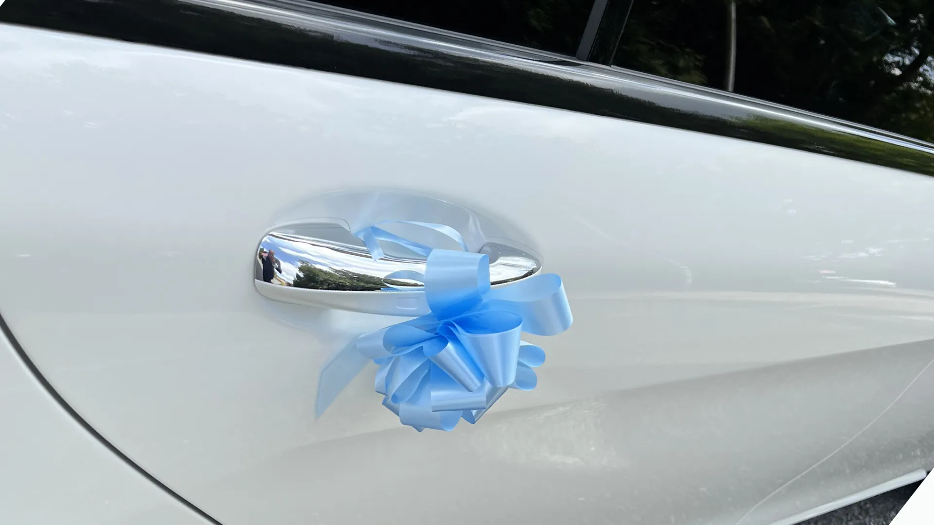 Light blue wedding bow attached to the door handle of a White Mercedes Car