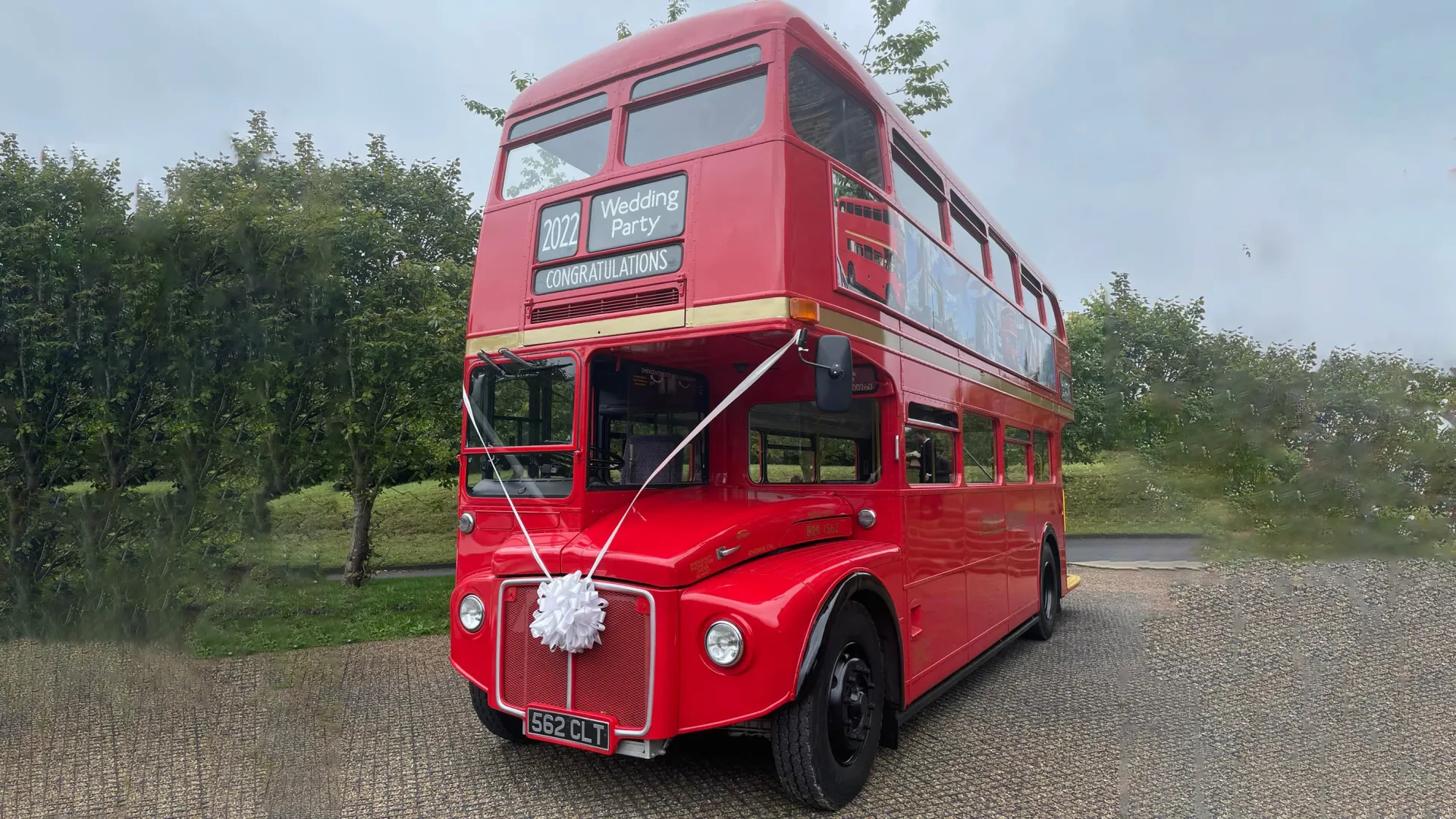 Big Red Double Decker Routemaster Wedding Bus decorated with white ribbons