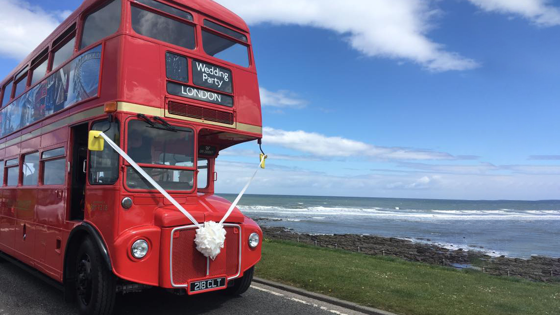 Red Routemaster Bus decorated with white wedding ribbons and bows parked by Sea side in Newcastle-Upon-Tyne