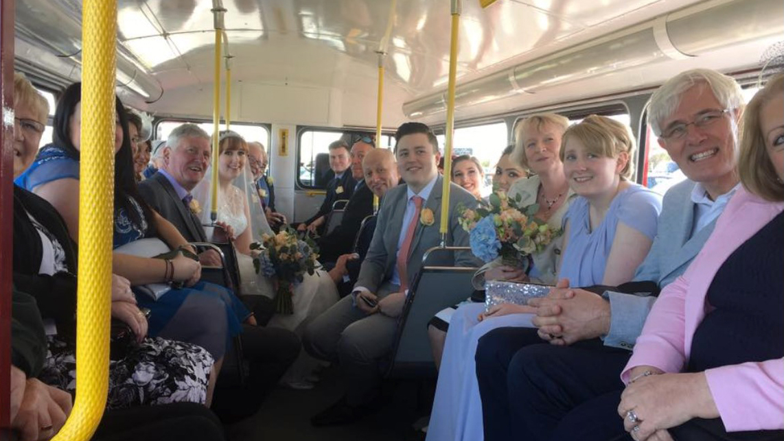 Wedding guests seated on the lower decker of a classic red routemaster bus