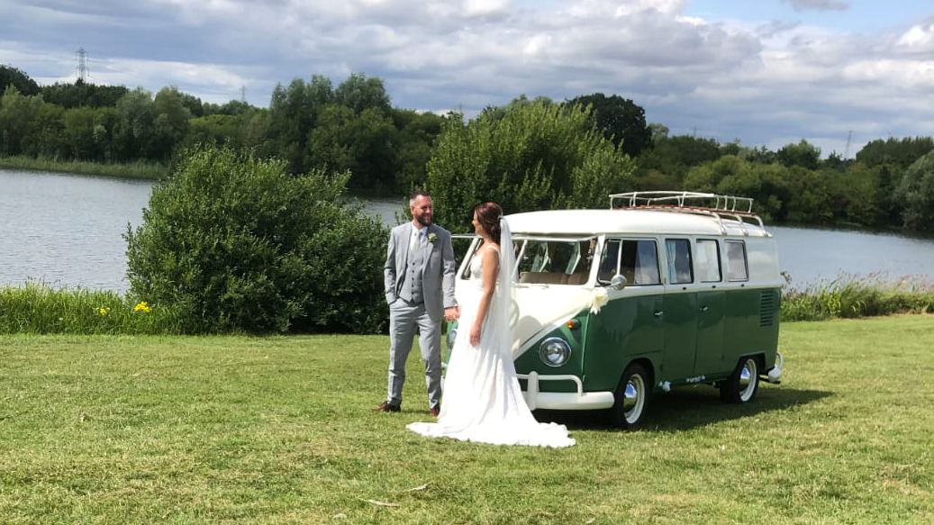 Bride and Groom standing in front of a Classic Green and White VW Campervan