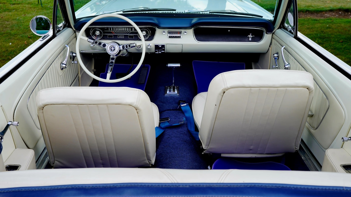 Aerial photo of a classic ford Mustang with convertible roof down showing the white leather inteerior and Royal Blue Carpet