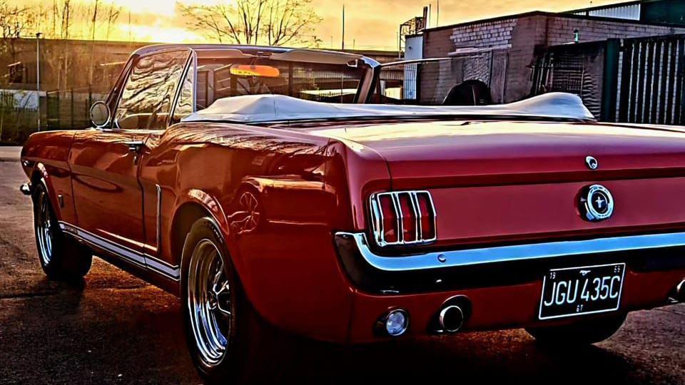 Rear view of a convertible Ford mustang in Red at sunset