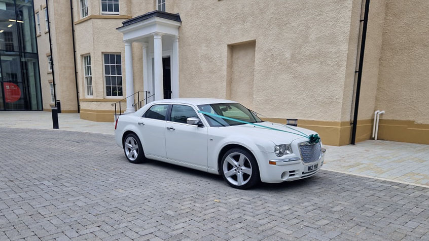 White Chrysler 300c Saloon Car with wedding ribbons and bows in front of registrar in Durham