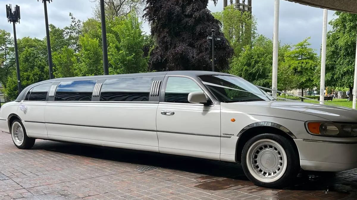 Right side view of a white Stretched limo with black roof