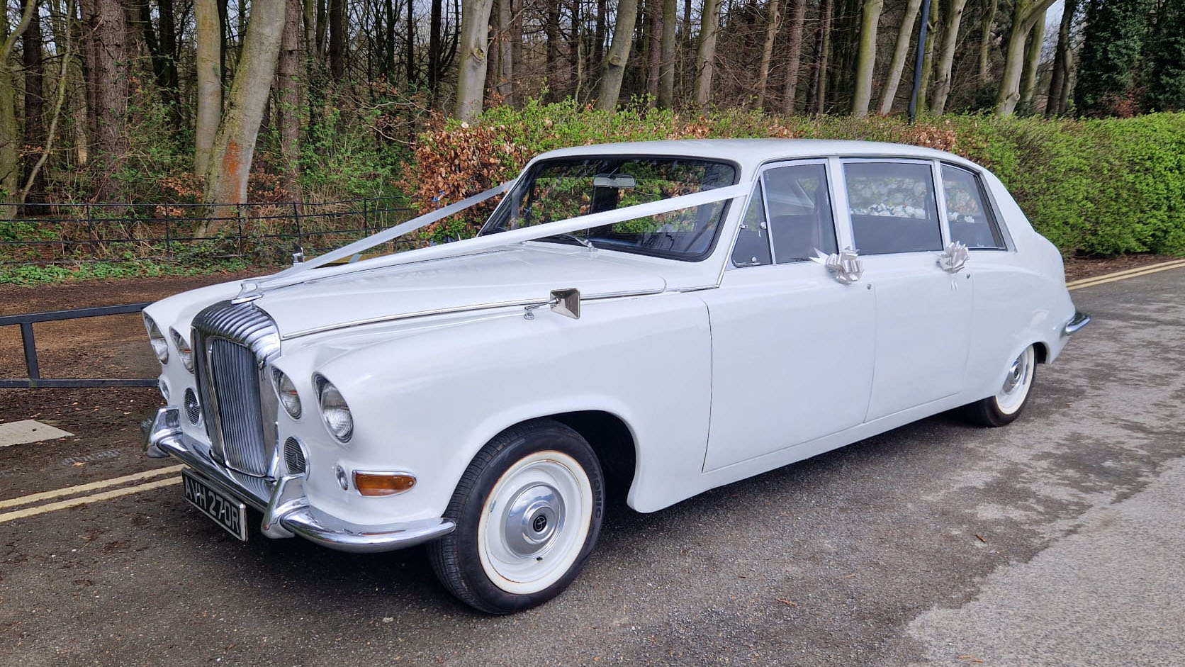 Classic daimler DS420 Limousine with wedding ribbons and large white wall tires.