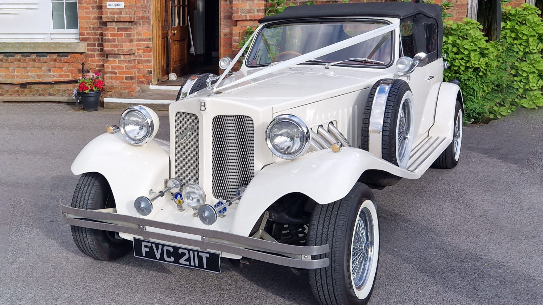 Front view of a vintage Beauford convertible decorated with wedding ribbons