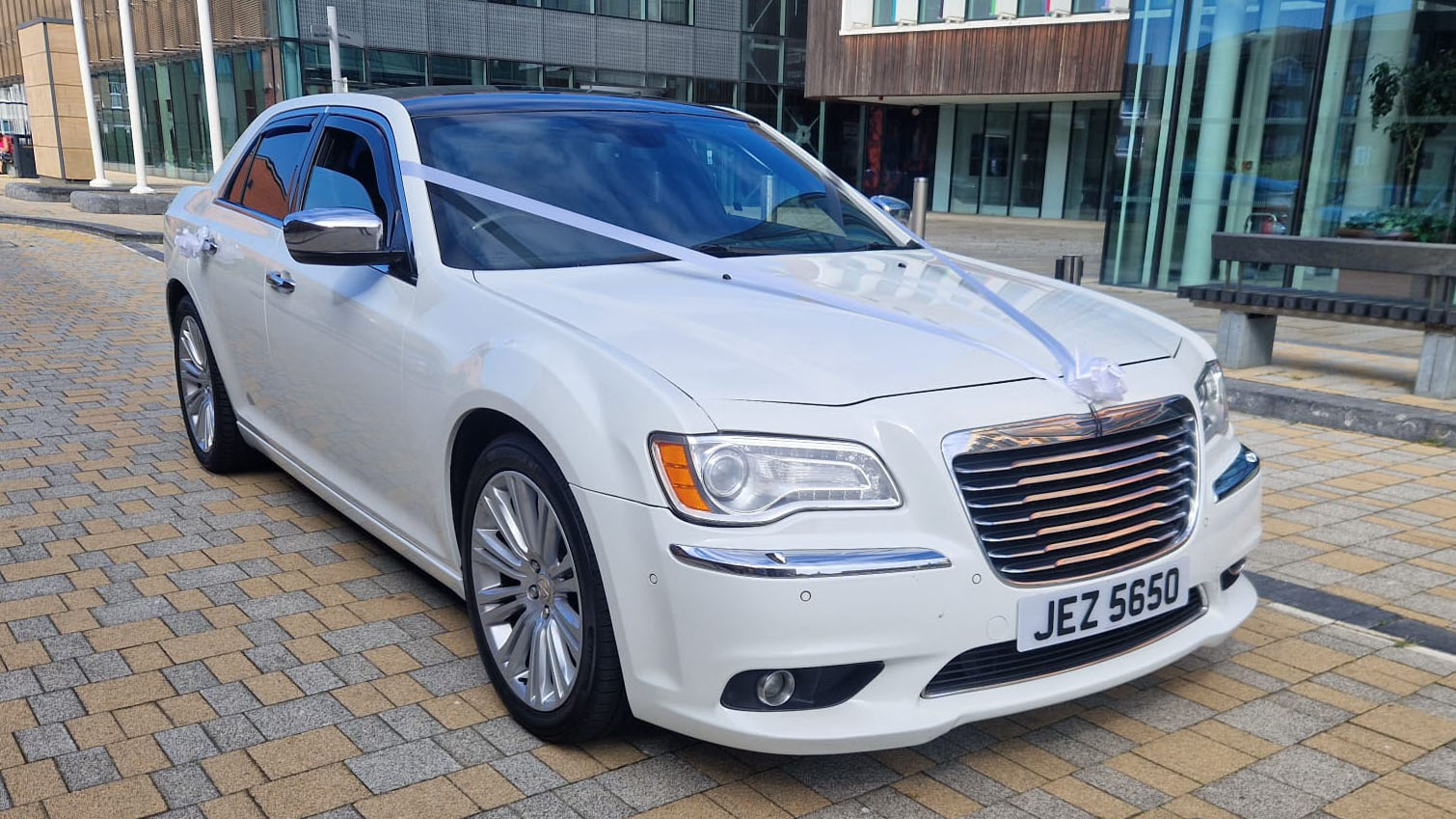 White Chrysler 300c saloon car with white ribbons at a wedding venue in Durham