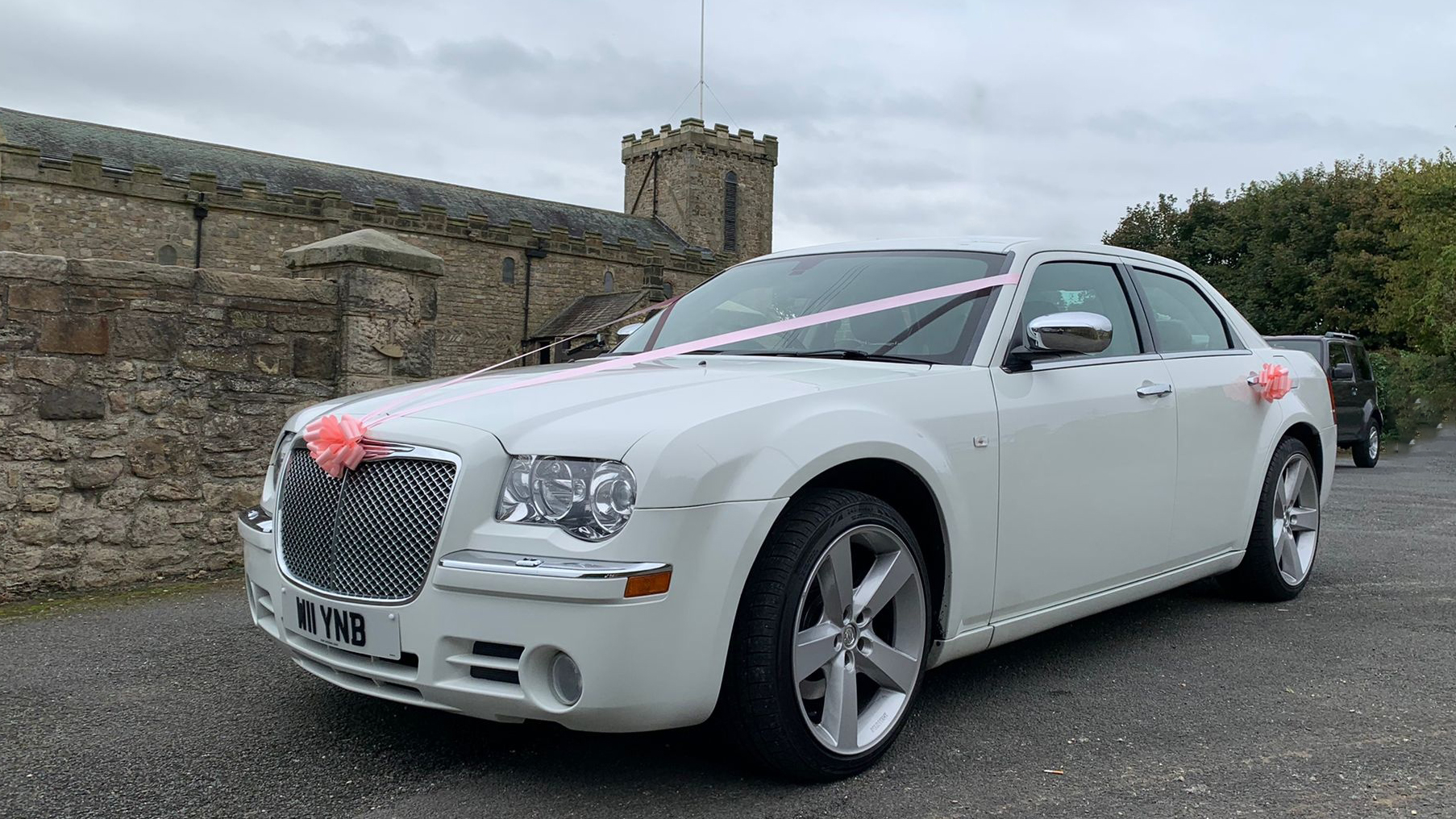 White Chrysler 300c Saloon Car with light pink wedding ribbons and bows