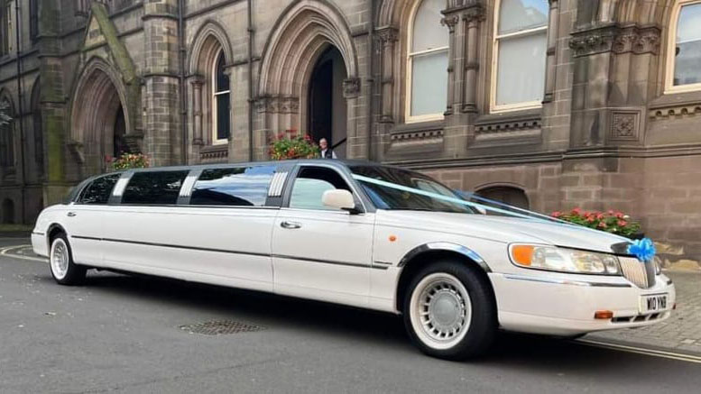 American Lincoln stretched limousine parked in front of a wedding church and decorated with Blue ribbons and bows