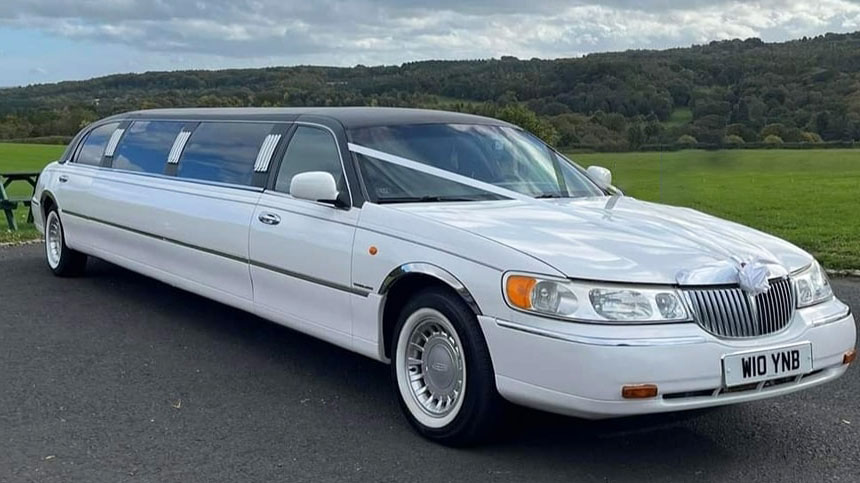 White Stretched Lincoln Limousine with black Roof decorated with white wedding ribbons