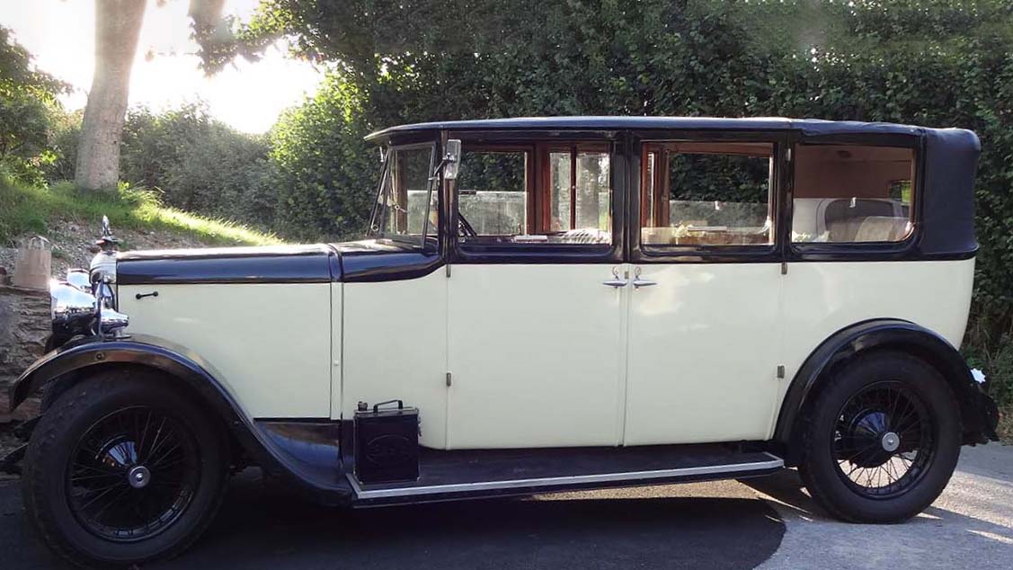 Left side view of Cream vintage wedding car with soift top black roof closed