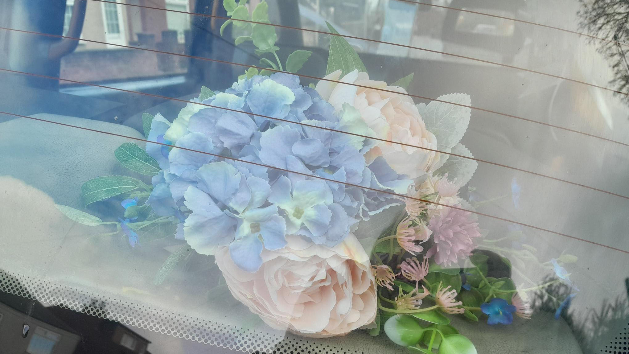 Bouquest of flowers on rear parcel shelf through the rear window.