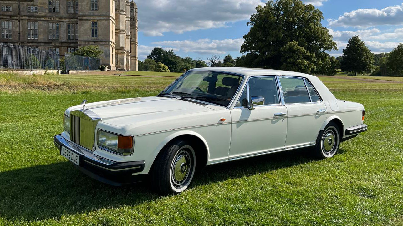 classic Rolls-Royce Silver Spirit in white parked in a green field