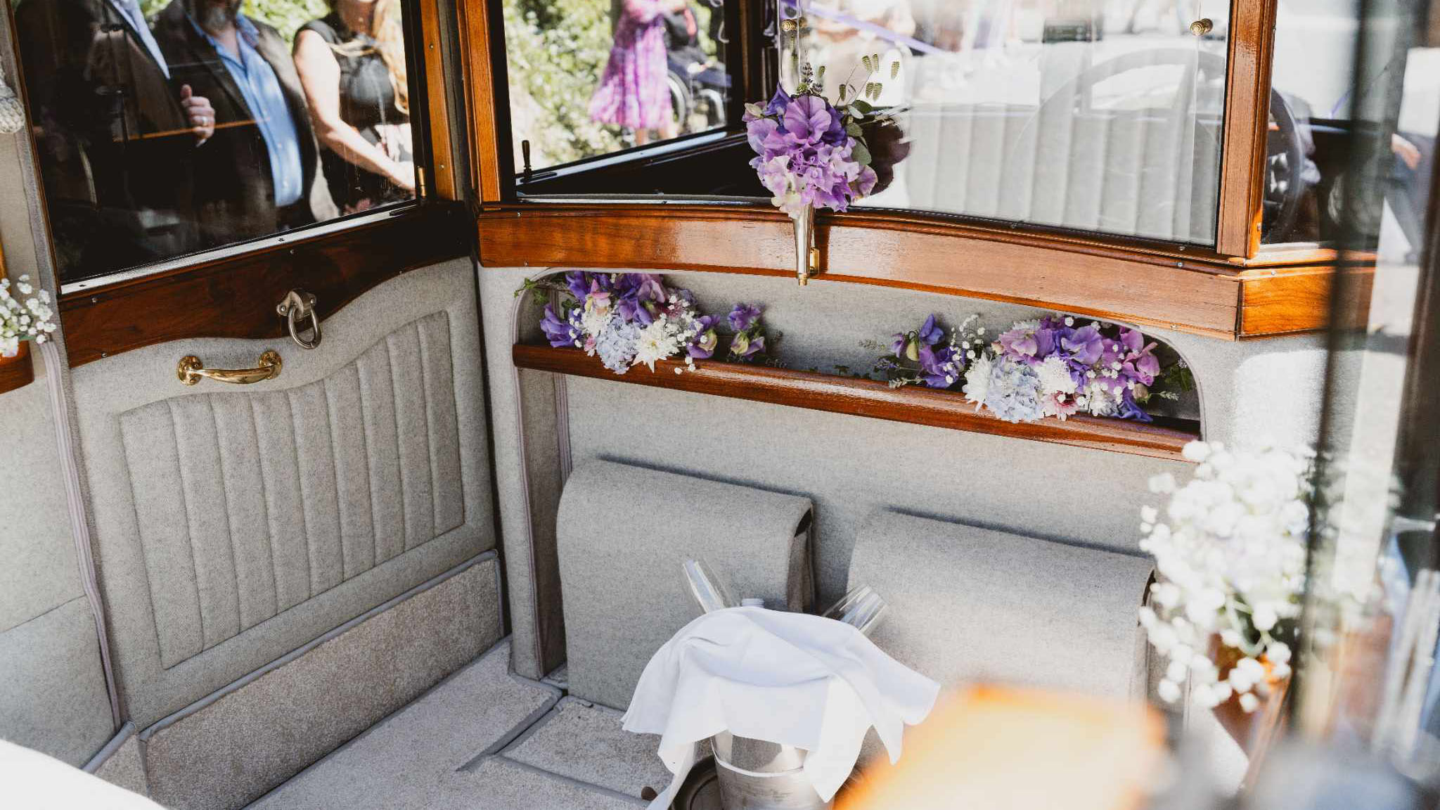 rear interior seats with silver cloth seating, wood features, privacy window decorated with light purple flowers