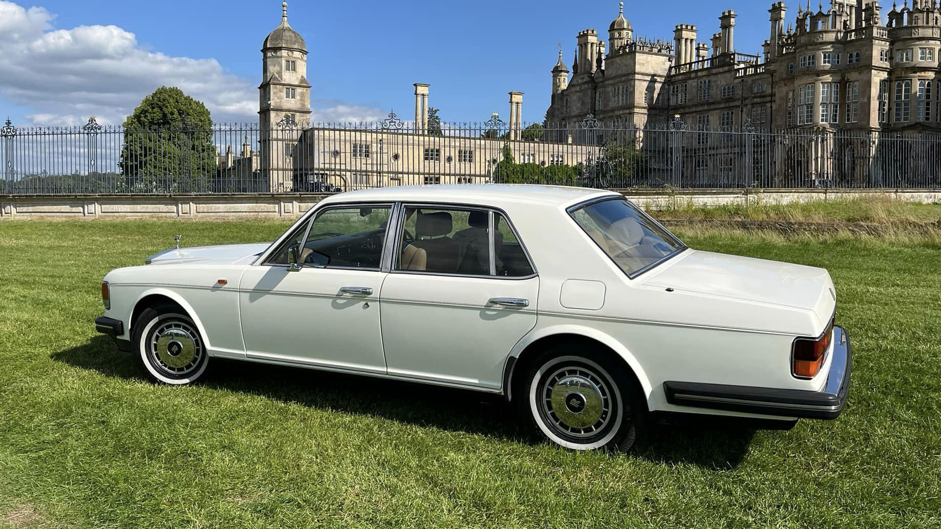 left side view of white Rolls-Royce Silver Spirit with castle in the background