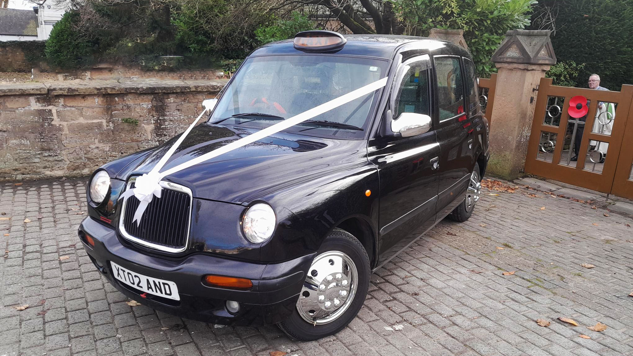 Modern Black Taxicab parked in frotn of a church dressed with white ribbons and bow