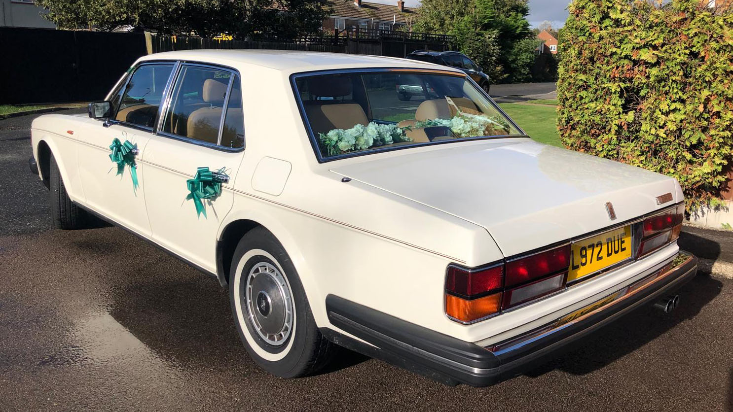 left rear view of classic Rolls-Royce Silver Spirit in white with Green ribbons on its door handles