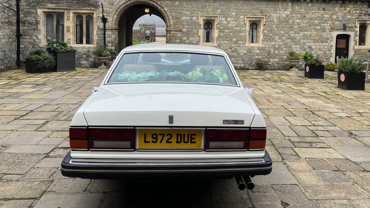 rear view of a classic white Rolls-Royce Silver Spirit parked in a courtyard